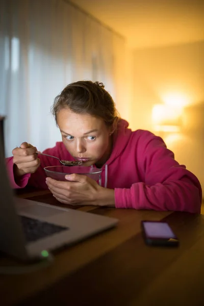 悪い習慣の概念 若い女性がテーブルで気をつけずに食べている間に彼女のスマートフォンに注意を払う — ストック写真