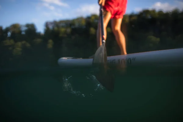 パドルボードの若い男 暖かい夜の日差しの中で美しい川で素晴らしい運動を得る パドル水中画像 — ストック写真