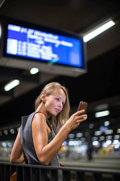 現代の駅で毎日の電車を待っている若い女性通勤者が 待っている間に携帯電話を使用しています カラートーン画像 — ストック写真