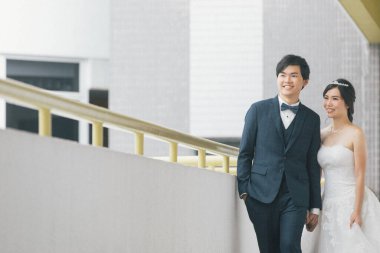 Mutlu gelin ve damat el ele tutuşup binanın yanında duruyor, düğün konsepti. 