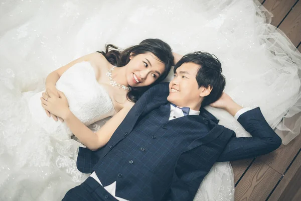木製の床に横になっている間幸せな花嫁と新郎ポージング 結婚式のコンセプト — ストック写真