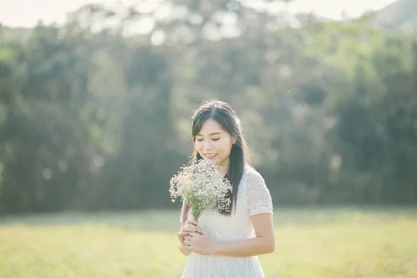 美丽的新娘 身穿白色婚纱 开着一束鲜花 在夏日的草地上 阳光普照 图库图片