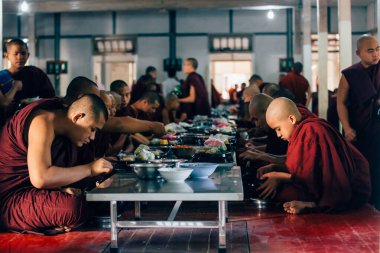 Genç rahipler 11 Ocak 2017 'de Mandalay, Myanmar (Burma) yakınlarındaki Mahagandayon Manastırı' nda öğle vakti benzersiz günlük yemeklerini toplamak için ellerinde kâseleriyle kuyruğa giriyorlar..