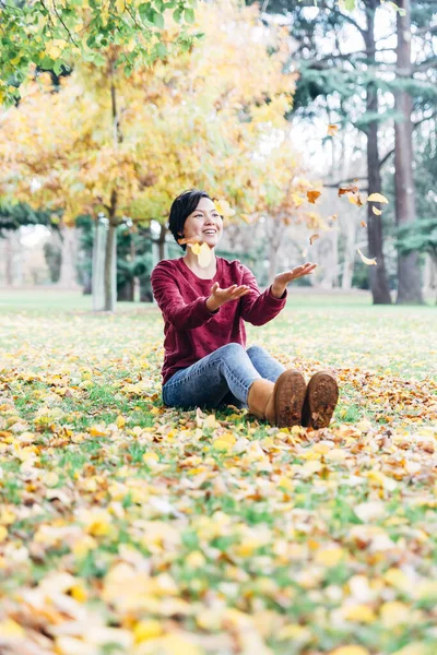秋天快乐的女人在树叶里玩耍 — 图库照片