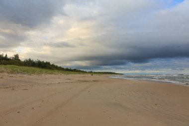 Yazın gün batımının bulutlu gökyüzü altında vahşi kumlu plaj, Palanga Resort, Litvanya, Avrupa