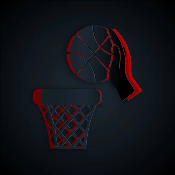 Рука с баскетбольным мячом и иконкой корзины изолированы на черном фоне. Мяч в баскетбольном кольце. Бумажный стиль. Векторная миграция — стоковый вектор