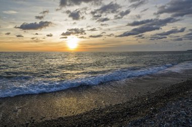 Lazarevskoye 'de gün batımında taş yığınıyla Karadeniz kıyısında bir sahil.