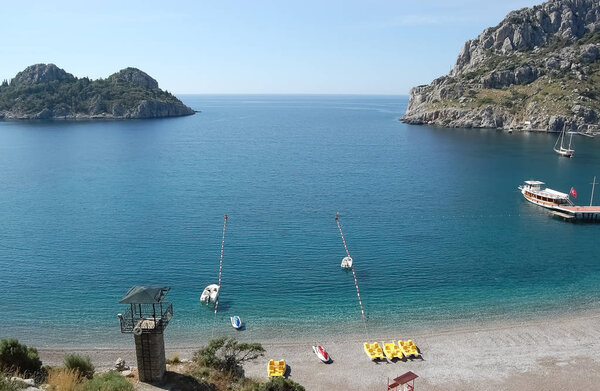 Вид на голубую лагуну с чистой водой, маленький зеленый остров и прогулочные лодки
.