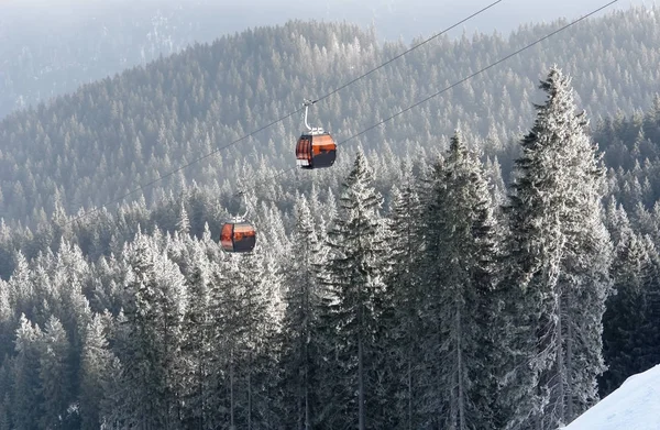 两个橙色小屋索道和雪被覆盖的云杉的树的看法 — 图库照片