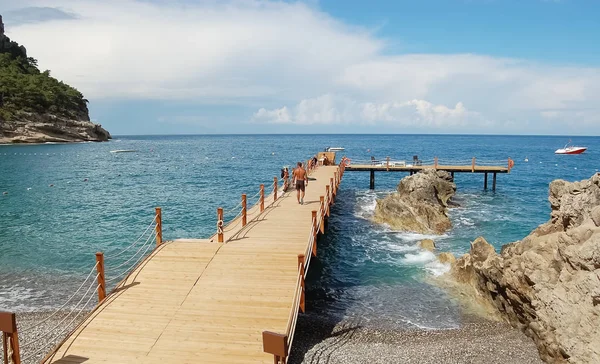 Чоловік ходить на дерев'яному пірсі, щоб плавати в морі . — стокове фото