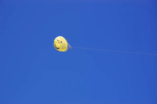 Gele parachute met een toerist op de achtergrond van een blauwe hemel. — Stockfoto