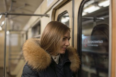 Moskova metrosu. Vagon içeride. Kız pencereden dışarı bakıyor.