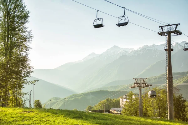 A canopy chairlift in the background of the mountains in the sum