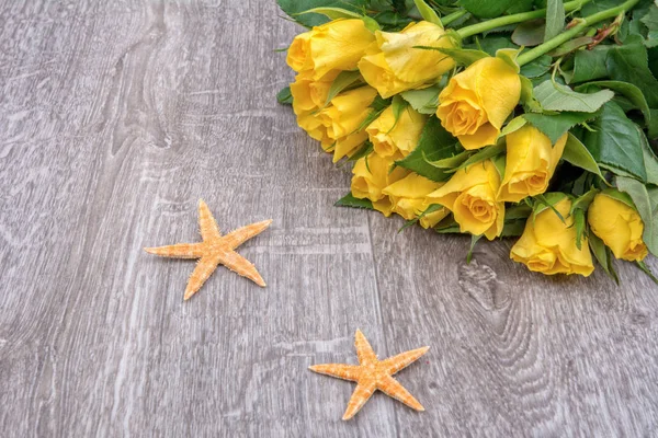 Estrellas de mar y rosas anaranjadas sobre fondo de madera — Foto de Stock