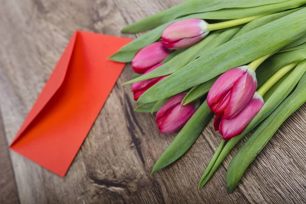 Red envelope with tulips on a wooden desk