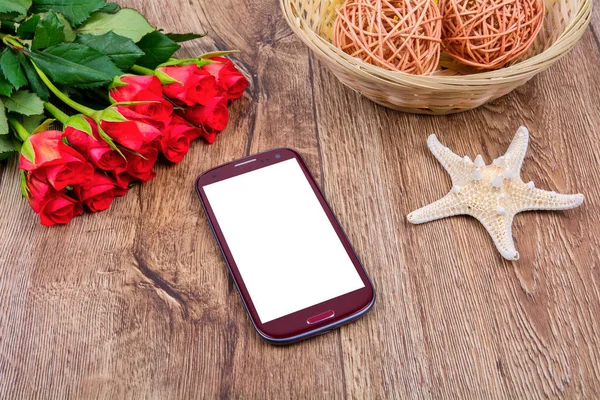 휴대 전화, 불가사리 및 장미 나무 테이블에 — 스톡 사진