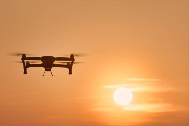 Yüksek çözünürlüklü dijital kamera üzerinde turuncu gökyüzü günbatımı hava uçan ile dron dört helikopter