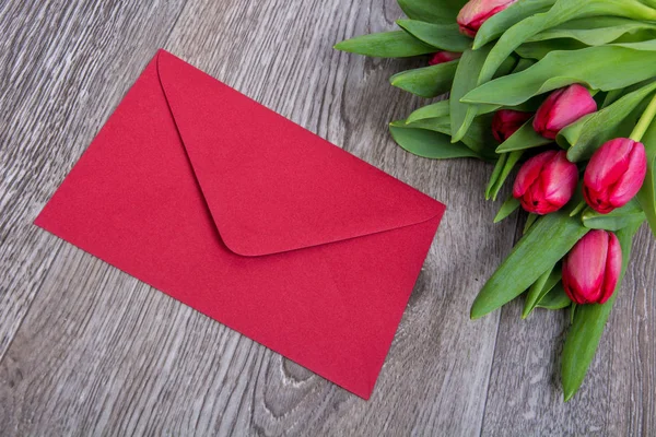 Rosa kuvertet med tulpaner på ett träbord — Stockfoto