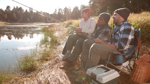 Farfar, far och pojke fiske vid en sjö — Stockvideo