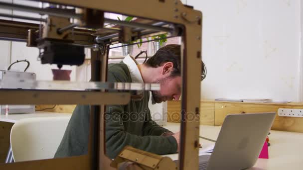 Дизайнер, работающий рядом с 3D принтером — стоковое видео