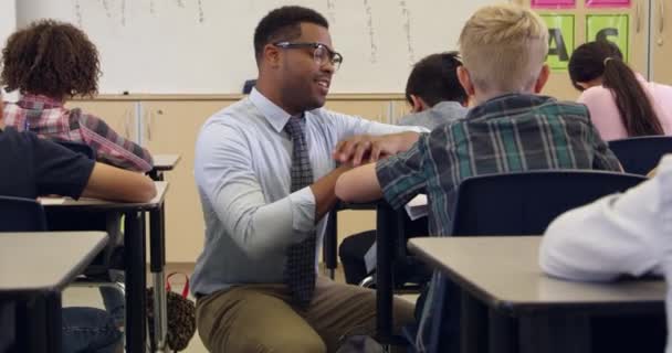 Profesor arrodillado para ayudar a un niño — Vídeo de stock