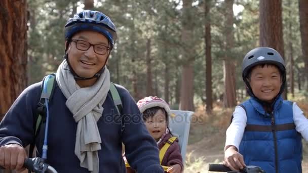 Família asiática em bicicletas em uma floresta — Vídeo de Stock