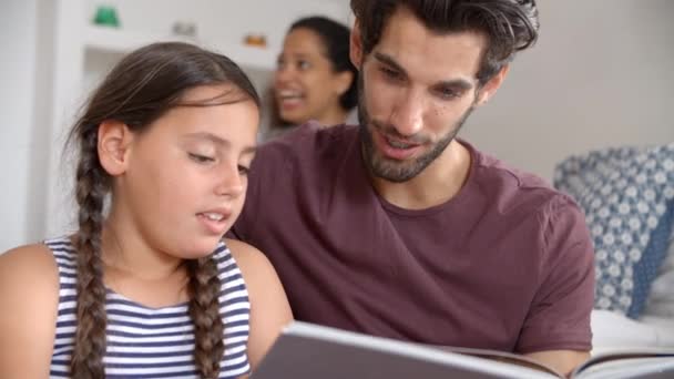 Familia sentada en el dormitorio libro de lectura — Vídeos de Stock