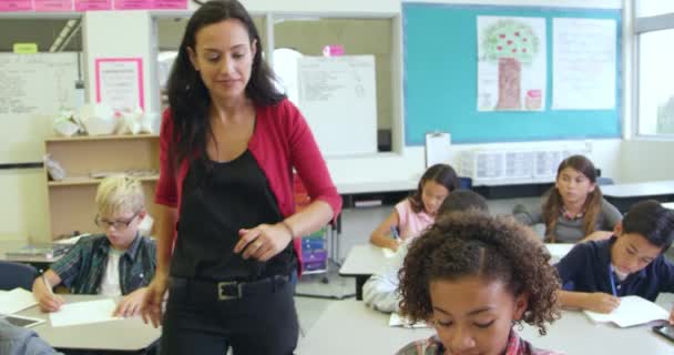 Teacher helping pupil at her desk — Stock Video