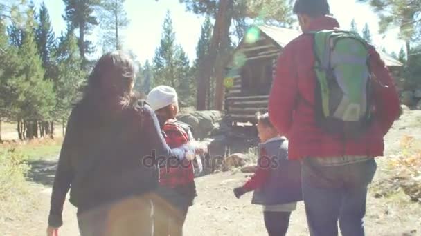 Семейная прогулка мимо хижины в лесу — стоковое видео
