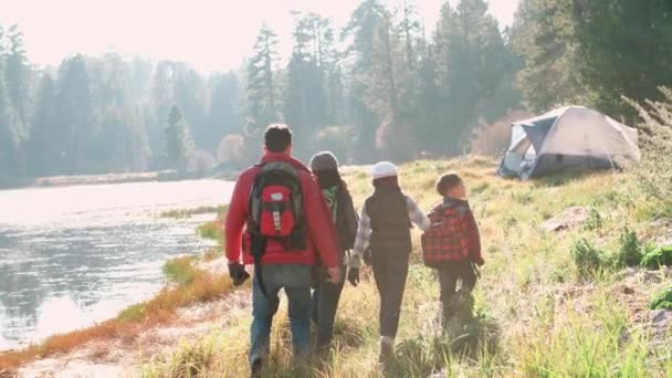 Föräldrar med barn gå nära en landsbygdens sjö — Stockvideo