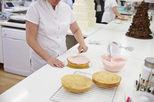 Frau dekoriert Kuchen mit Zuckerguss — Stockfoto