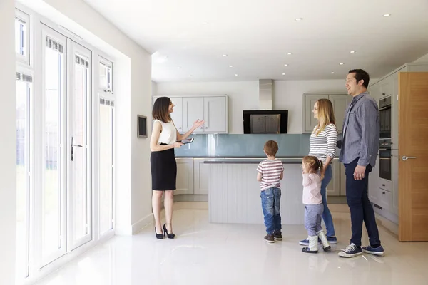 Agente immobiliare che mostra la famiglia intorno alla proprietà in vendita — Foto Stock