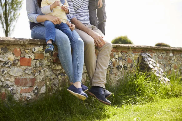 Familie sitzt beim Spaziergang auf Mauer — Stockfoto
