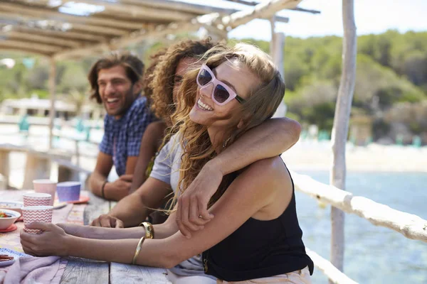 Amigos sentados en una mesa junto al mar — Foto de Stock