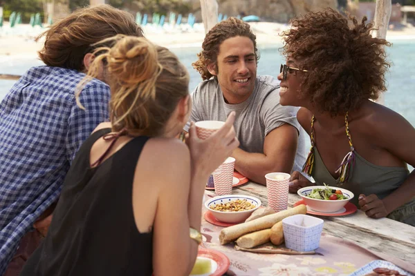 Amigos hablando a través de una mesa en la playa — Foto de Stock