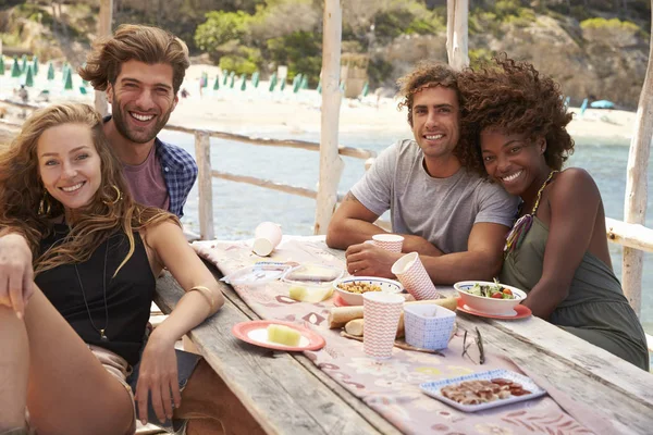 Friends sitting at a table by the sea — Stock Photo, Image