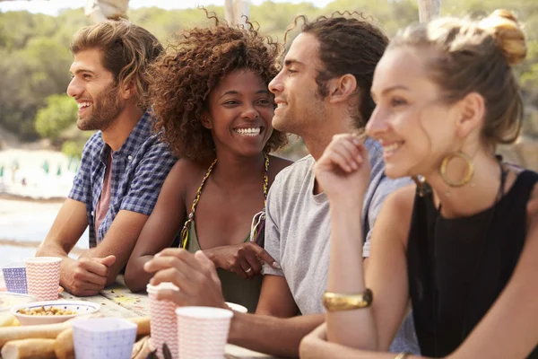 Vrienden zitten aan een tafel door de zee — Stockfoto