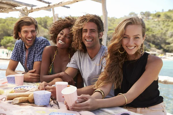 Vrienden zitten aan een tafel door de zee — Stockfoto