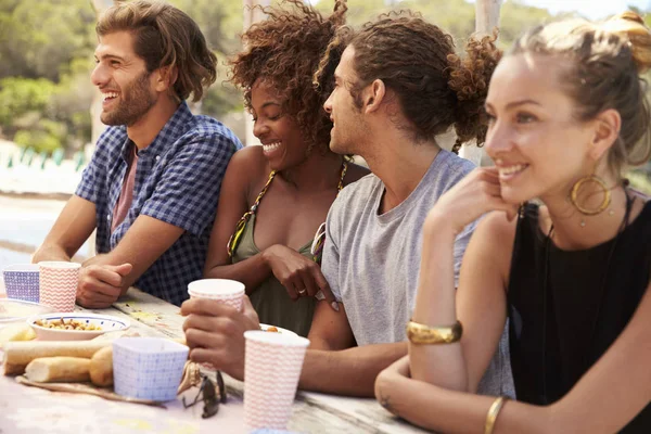 Freunde sitzen an einem Tisch am Meer — Stockfoto