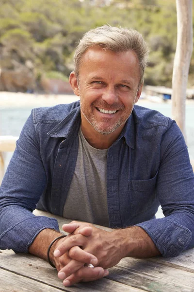 Homme d'âge moyen à une table au bord de la mer — Photo