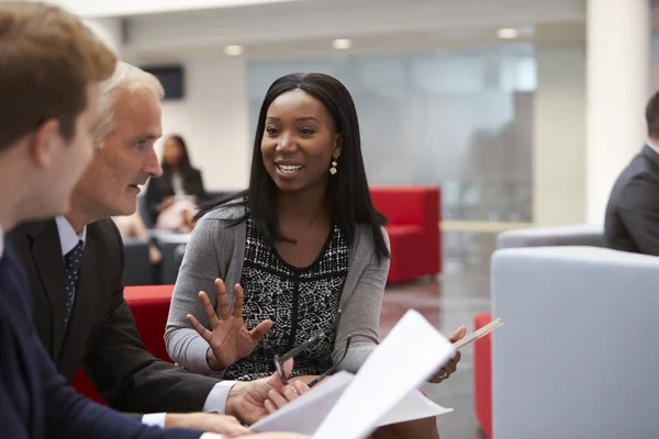 Geschäftsleute diskutieren Dokument in Lobby — Stockfoto