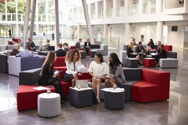 Mujeres de negocios se reúnen en el vestíbulo ocupado de la oficina moderna — Foto de Stock