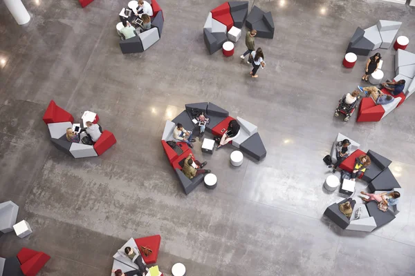 Studenten groepen zitten in een atrium van de Universiteit — Stockfoto