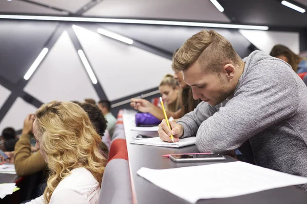 Estudante do sexo masculino tomando notas em uma palestra — Fotografia de Stock