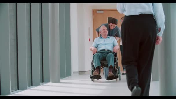 Медсестра толкает пожилого пациента в инвалидном кресле — стоковое видео