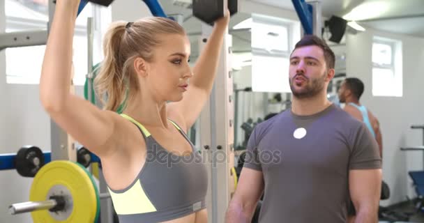 Entrenador asesorando a una mujer que hace ejercicio con pesas — Vídeos de Stock