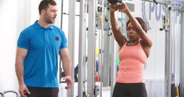 Mulher usando um peso kettlebell com um treinador — Vídeo de Stock