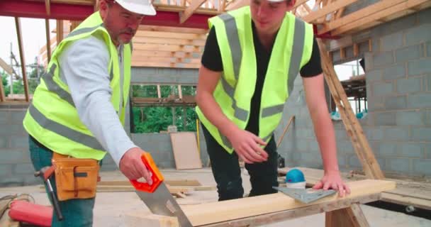 Menuisier avec apprenti mâle coupe du bois — Video