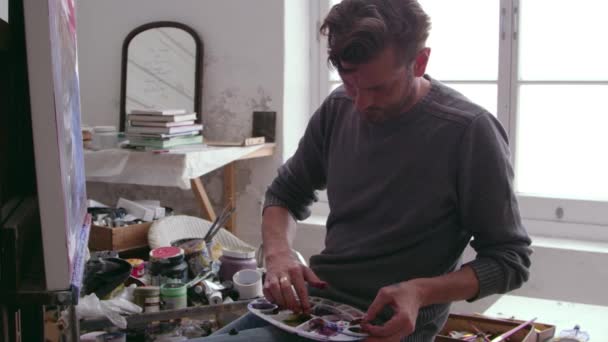 Художник кладет масляную краску на палитру — стоковое видео