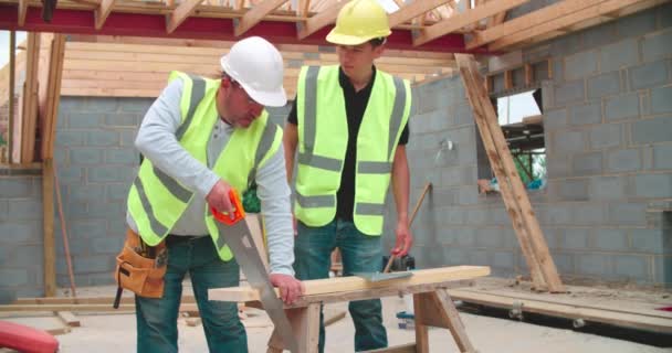 Carpenter With Male Apprentice Cutting Wood — Stock Video